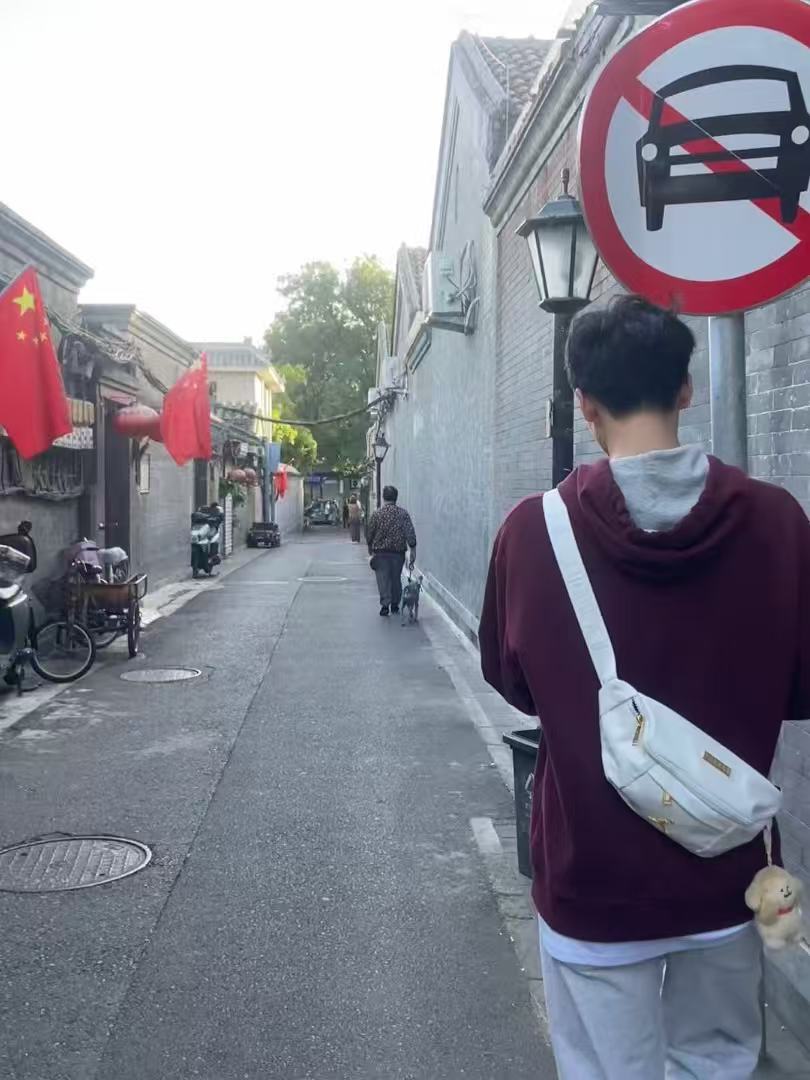 Zikai Zhou walking in a Beijing hutong